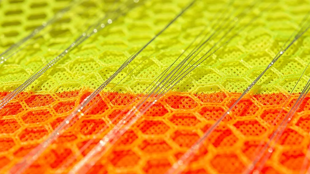 Détail macro d'un tissu technique haute visibilité respirant avec structure alvéolaire