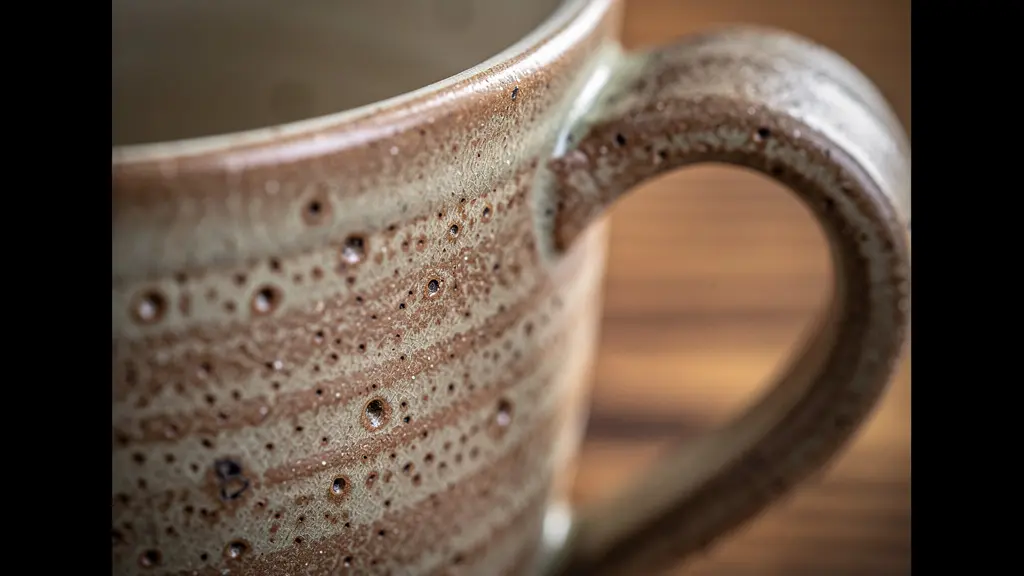 Gros plan sur un mug en céramique artisanale avec texture naturelle posé sur une table en bois